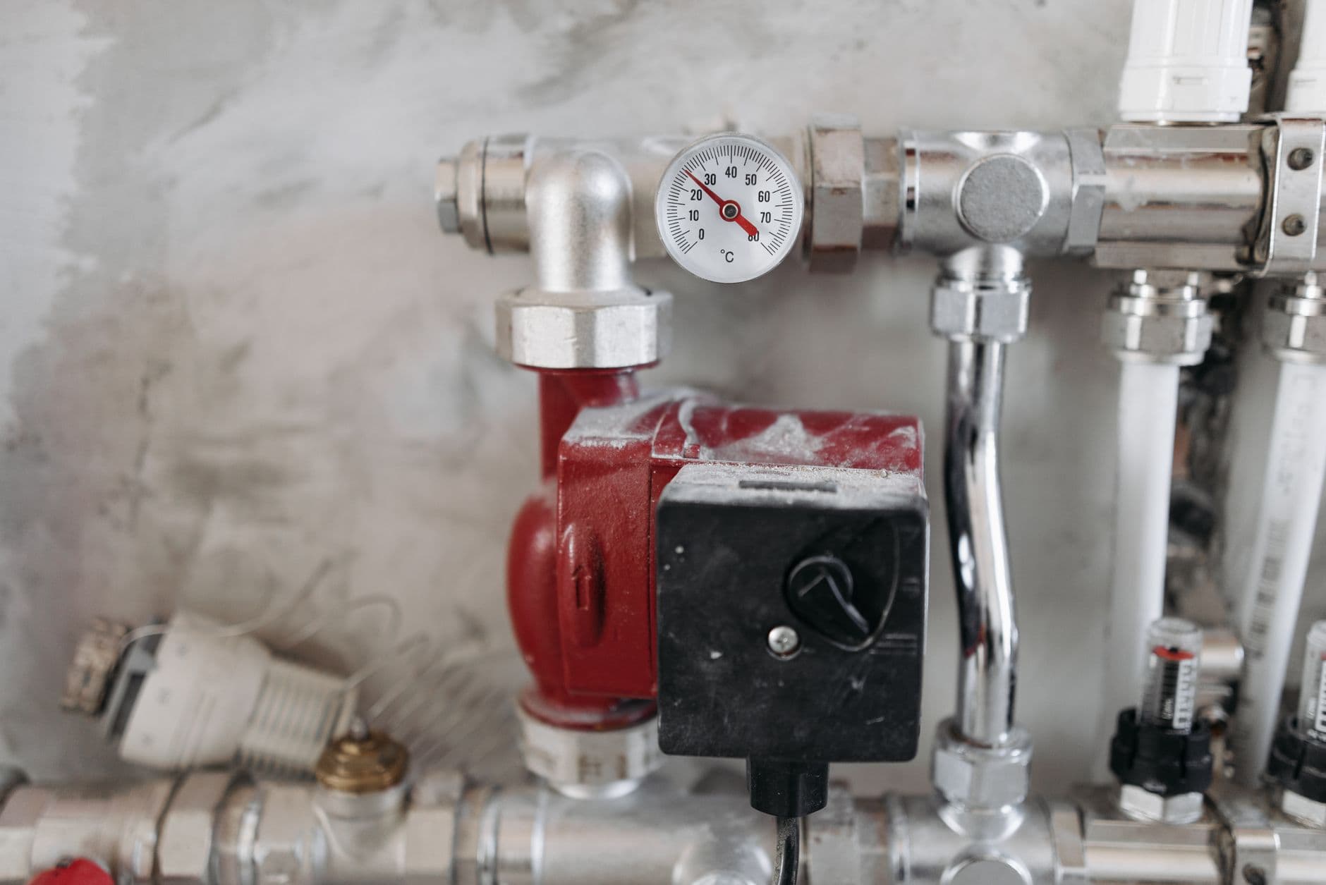 A circulator pump and temperature gauge on a domestic heating manifold
